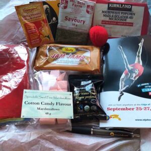 Items from a circus themed conference in a box, including candy, conference program, popcorn, cookies, and a clown nose