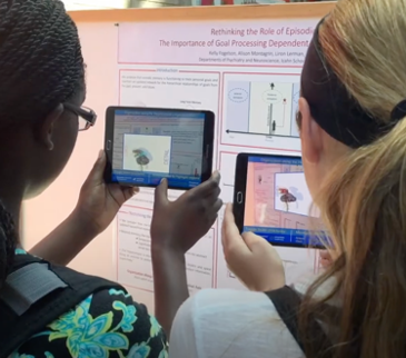 Two women holding up iPads to view augmented reality on a poster